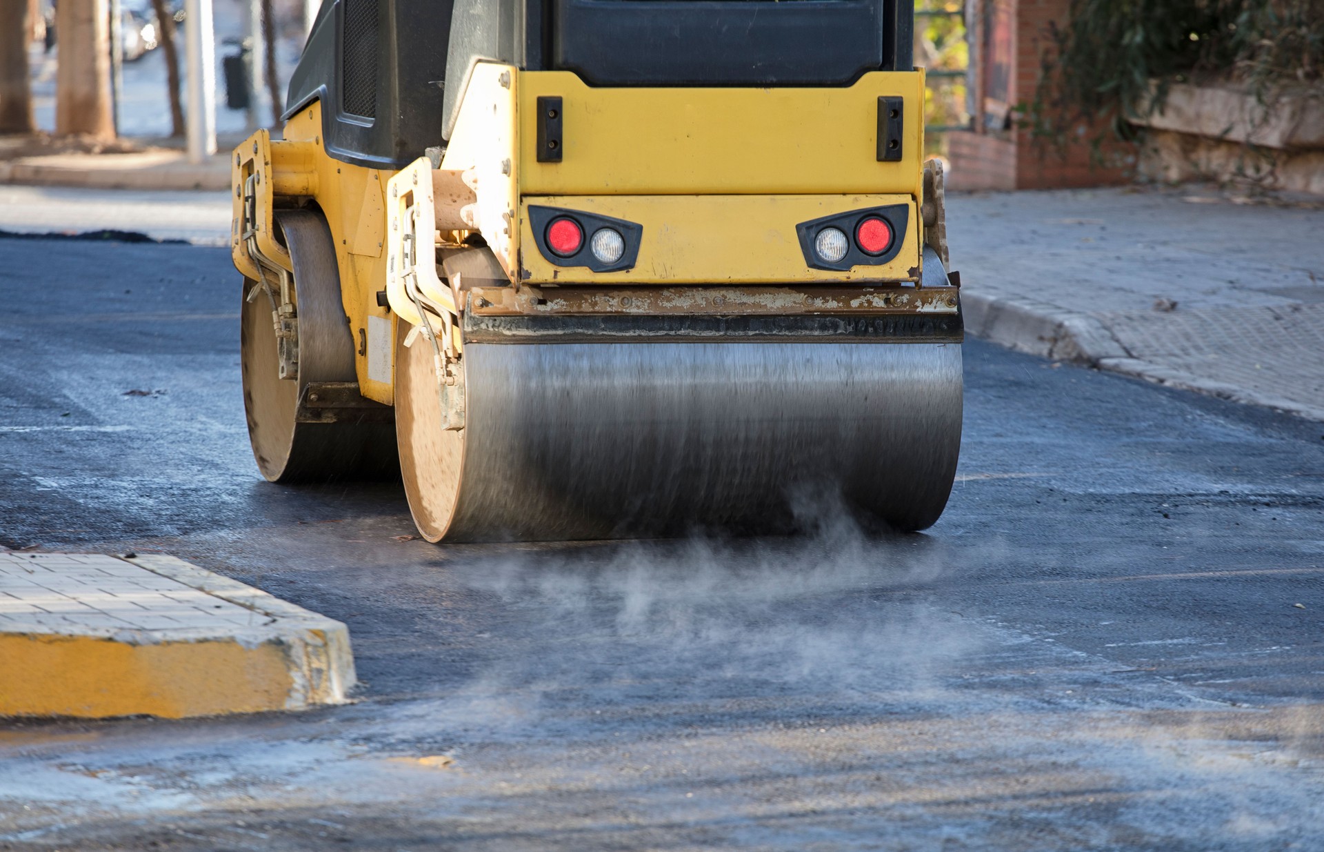 Road roller and asphalt paving machine at construction site